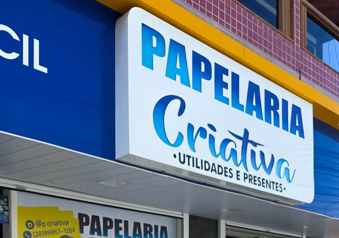 Fachada da Papelaria Criativa na Av. Etelvina Vivacqua: placa branca com letras azuis, toldo azul e a vitrine com o banner da loja